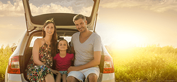 Familydrive 365X170 Young family of three posing in the back of a vehicle on a sunny day