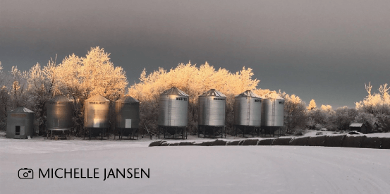 Winter image of grain bins and bales