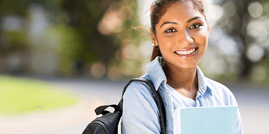 Student holding books smiling