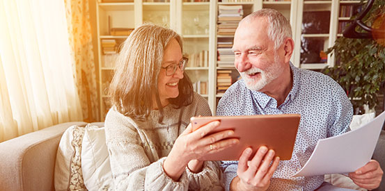Smiling mature couple holding tablet