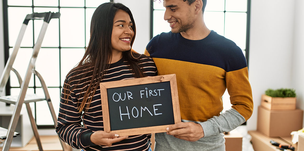couple holding a our first home sign