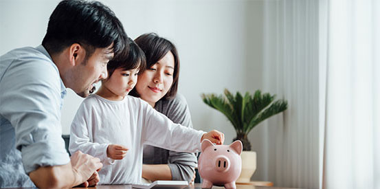 Mom, dad and daughter putting coins in a piggy bank